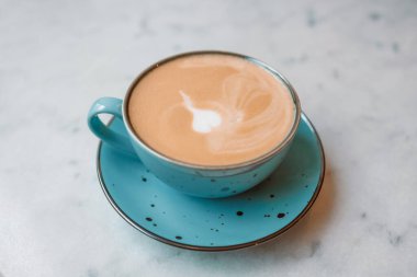 Kafe masasında kahve fincanındaki Latte sanatı. Köpükle çizilmiş Rosetta çiçeğinin yakın çekimi.