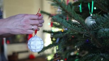 Noel ağacı süslemek. Noel ağacını süsleyen adamın elleri, arka planda parlak şenlik ışıklarıyla çevrili.. 
