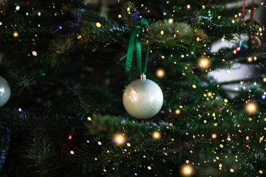 Noel ağacındaki beyaz topları kapatın. Arka planda Bokeh çelenkleri. Yeni yıl konsepti. 2023