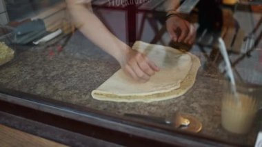 A female hand is greasing cinnamon rolls with a yolk. Homemade pastry on baking sheet lined with parchment. Cooking process of traditional swedish buns kanelbullar. Close up. 