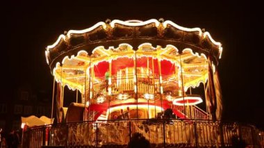 Old carousel in the park. Three horses and a plane on a traditional fair carousel at night. Carousel with horses during a summer evening in Poland. Blurred background