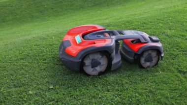 Robotic Lawn Mower on green grass background.Automatic robot lawnmower in modern garden.Green grass trimming with lawn mower. High quality 4k footage