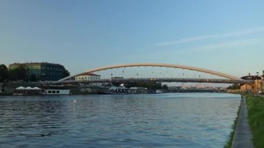 4k Vistula river in Krakow, Poland with blue metal Bridge arch bridge over at sunset