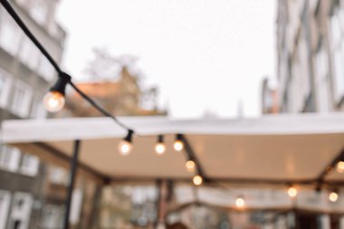 Light garland on the street at the evening. Decoration of the street with vintage bulbs garland, festive city decorations for cafe and restaurant, celebrating, lights as exterior decor 