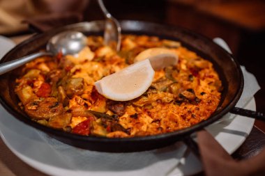 İspanya 'nın klasik yemeği, geleneksel deniz ürünleri paella' sı kırsal mavi beton arka planda. İspanyol paella karides, klemp, midye, yeşil bezelye ve taze limon dilimleri. 