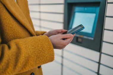 Paketi depolamak için kırmızı otomatik oto servis terminali ya da dolap kullanan akıllı telefonu tutan kadın. Yüksek kalite fotoğraf