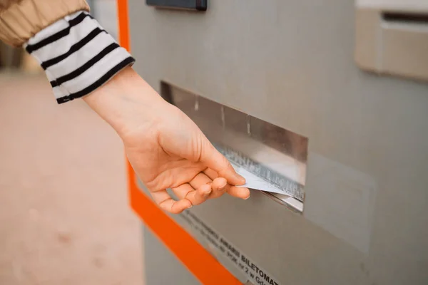 Closeup of woman paying for service underground parking or buying a subway or train ticket using an electronic self-service kiosk, takes a printed check from an ATM