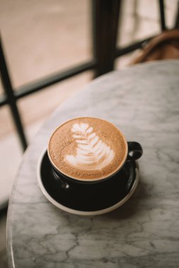 Beyaz arka planda latte sanatıyla siyah kapuçino. Güzel köpük, yeşillik seramik kaplar, tarz tonu, yazı için yer. Yüksek kalite fotoğraf