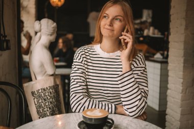 Kafede kahve içerken cep telefonu kullanan mutlu güzel bir kadın. Yüksek kalite fotoğraf