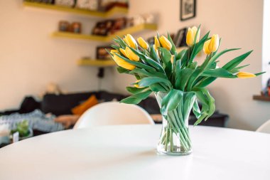 Salondaki beyaz ahşap masada cam vazoda bahar çiçekleri. Sarı lale buketi. Çağdaş zarif bir iç mekan. Yüksek kalite fotoğraf