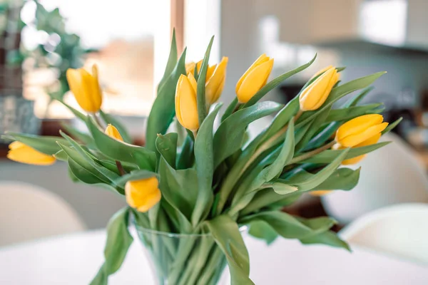 Salondaki beyaz ahşap masada cam vazoda bahar çiçekleri. Sarı lale buketi. Çağdaş zarif bir iç mekan. Yüksek kalite fotoğraf