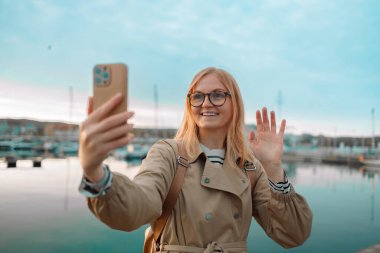 Mutlu 30 'lar hipster kız blogcu nüfuzlu blogcu vlog kaydını tutuyor kameraya bakıyor, video çekiyor, Sopot, Gdansk rıhtımında yayın yapıyor. Sonbaharda Avrupa 'yı geziyorum. Yüksek kalite fotoğraf