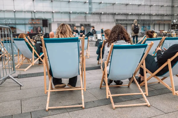 ポーランド クラクフ2022年5月28日 オープンエアの会場で講師の話を聞き 木製の椅子ラウンジャーで企業ビジネスセミナーのマスタークラスで登壇者の話を聞く — ストック写真