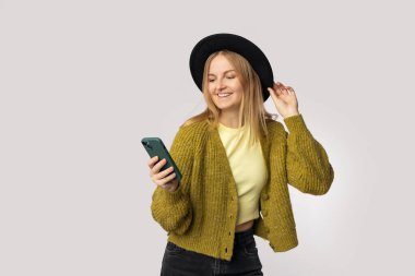 Gri arka planda izole edilmiş cep telefonu kullanan heyecanlı beyaz kadın gülüyor. Yüksek kalite fotoğraf