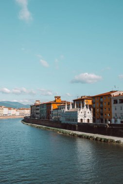 Pisa, İtalya 'daki Arno nehri boyunca binaların güzel bir manzarası. Nehrin üzerinden bir köprü geçiyor ve her iki taraftaki evler denize bakıyor. Yüksek kalite fotoğraf