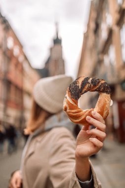 Polonya, Krakow 'da pazar meydanında elinde çubuk kraker tutan şık elbiseli güzel bir bayan turist. Yüksek kalite fotoğraf