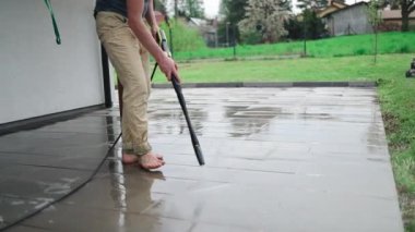 Verandadaki taş levhaları yüksek basınçlı temizleyiciyle temizliyorum. Dışarıdaki zemini temizleyen bir işçi.. 