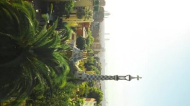 BARCELONA, İSPAIN - 13 Ekim 2022: Guell Park 'tan Barcelona şehri sabah manzaralı renkli mozaik binalar ve turist parkı Park Guell. Barselona, İspanya. Kamera tepsisiyle. Yüksek