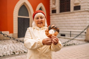 Krakow 'daki eski şehir merkezi manzarasına karşı elinde prezel, geleneksel Polonya çerezi tutan yaşlı kadın.. 