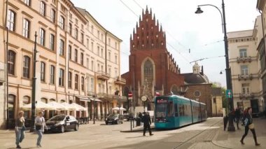 Krakow, Polonya - 3 Mayıs 2023: Krakow caddesindeki modern tramvay. Toplu taşıma. İnsanlar otobüs durağında tramvayı bekliyor. Ulaşım konsepti. Yüksek kaliteli FullHD görüntüler