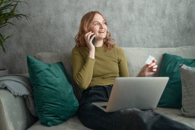 Evdeki koltukta oturan cep telefonu kullanan genç bir kadın. Ekommerce mağazasından akıllı telefon alan, internetten video izleyen, mesajlaşan ya da sosyal medya haberlerini kontrol eden oldukça rahat bir bayan. Yüksek