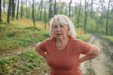 50 'lerin son sınıf 60' lı yılların sporcusu. Parktaki zor egzersizden sonra zor nefes alan kardiyo egzersizlerinden yorgun düşmüş. Kafkas zindeliği olan kadın kas ağrısı ya da kramp geçiriyor. Yüksek kalite fotoğraf