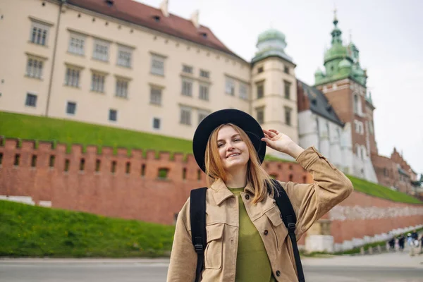 Sarışın, çekici bir kadın saçlarını toplamış ve harika bir gülümsemeyle Wawel Kalesi, Cracow, Polonya yakınlarında kameraya bakıyor ve gülümsüyor. İlkbaharda Avrupa 'yı geziyorum. Yüksek kalite fotoğraf