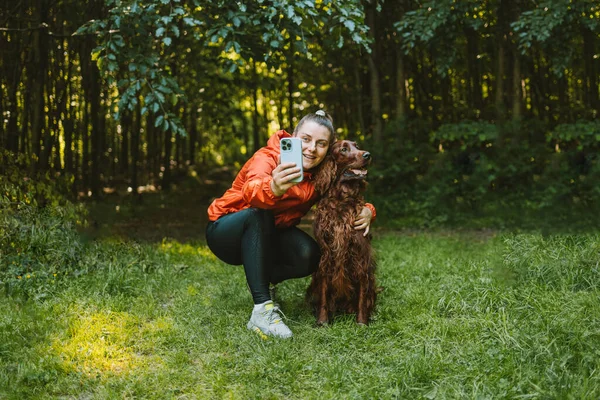 快乐的高加索女孩徒步旅行者带着她可爱的爱尔兰猎狗在夏日的森林里散步 探险和发现 — 图库照片