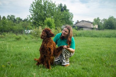 Beyaz kadın, İrlandalı köpek yavrusuna sarılıyor sevimli, kırmızı köpek dostu yakın plan, kapalı gözler, komik hayvanlar. Parktaki köpek ve sahibi arasındaki sevgi ve arkadaşlık. Gerçek dostlar, insanların evcil hayvanları.