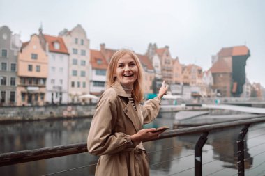 Polonya, Krakow caddesinde elinde akıllı telefonuyla dolaşan çekici genç, şık sarışın kadın. Yüksek kalite fotoğraf