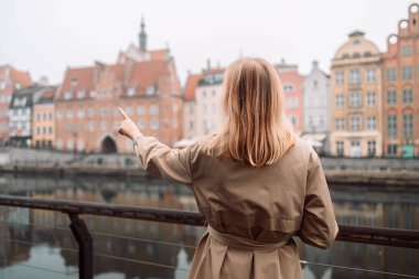 Polonya, Krakow caddesinde elinde akıllı telefonuyla dolaşan çekici genç, şık sarışın kadın. Yüksek kalite fotoğraf