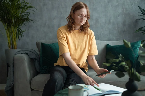 Genç sarışın kadın, internet üzerinden vergi makbuzlarını ödemeden önce hesap makinesinde mali belgelerle çalışıyor. Milenyum kadınlarının bütçe planlaması ekonomiden tasarruf şansı bulduğu için memnun.