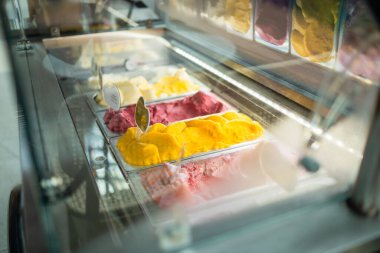 Metal tepsilerde sergilenen yaz alışverişleri gibi çeşitli dondurma tatları satan bir mağazada veya dondurmacıda pencere görüntüsü. Yüksek kalite fotoğraf