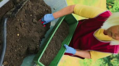 Bahar hobisi, yeşil plastik saksıda nakledilen güzel beyaz kadın, bahçedeki masada kirli ya da toprağın olduğu ev, bahçe bitkisi, yeşil tropikal, güzellik ve...