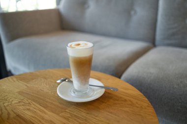 Coffee in blue cup on wooden table in cafe with lighting background. High quality photo