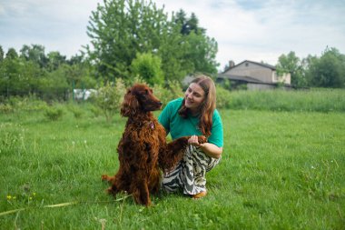 Bahar bahçesinde kucağında İrlandalı bir köpek yavrusu tutan güzel bir kız. Köpekler gülümsüyor, komik hayvanlar, kopyalama alanı. 