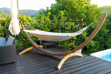 Hamak masalı ahşap terasta asılı. Üzüm bağının sanayi bölgesinde cennet köşesi kavramı