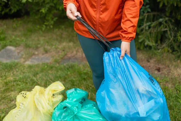 カラーパッケージの種類によるゴミの分類 環境廃棄物のリサイクル エコフレンドリーな人々はゴミを分類します 黄色いペーパー 赤い金属 緑のガラス 青いプラスチック — ストック写真