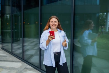 Mutlu iş kadını elinde dijital tabletle şehirde işe gidip gelirken telefonunda kısa mesaj okuyor. Yüksek kalite fotoğraf