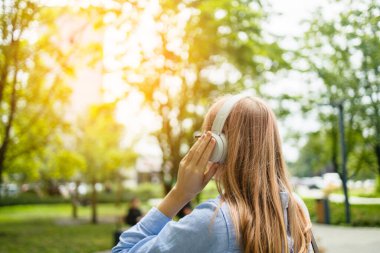 Takım elbiseli, kablosuz kulaklık takan, cep telefonuyla konuşan, cep telefonuyla konuşan şehir caddesinde yürüyen mutlu genç bir kadın. Yüksek kalite fotoğraf