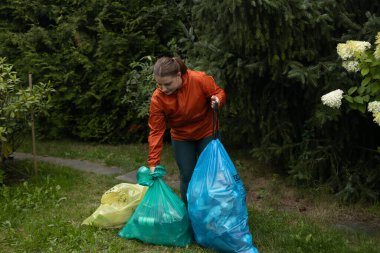 Çöpleri renkli paketlere göre sıralamak, çevresel atıkların geri dönüşümü. Çevre dostu insanlar çöpleri ayırır. Sarı kağıt, kırmızı metal, yeşil cam, mavi plastik. 