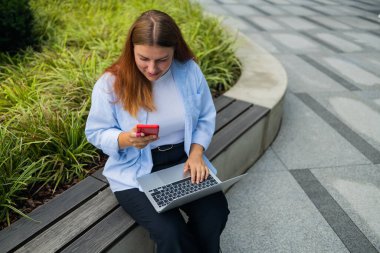 Resmi giyinmiş öfkeli bir kadın, içerik web sitesinde kendi şirketinin sorunları hakkında haberler okuyor ve uluslararası akıllı telefon konuşmaları sırasında çalışanlara bağırma ve yangın çağrısı yapıyor.