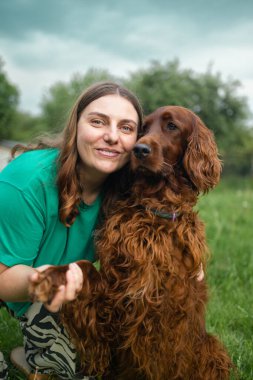 Bahar bahçesinde kucağında İrlandalı bir köpek yavrusu tutan güzel bir kız. Köpekler gülümsüyor, komik hayvanlar, kopyalama alanı. 