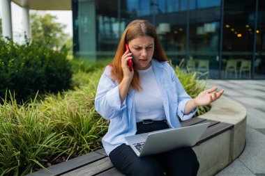 Resmi giyinmiş öfkeli bir kadın, içerik web sitesinde kendi şirketinin sorunları hakkında haberler okuyor ve uluslararası akıllı telefon konuşmaları sırasında çalışanlara bağırma ve yangın çağrısı yapıyor.