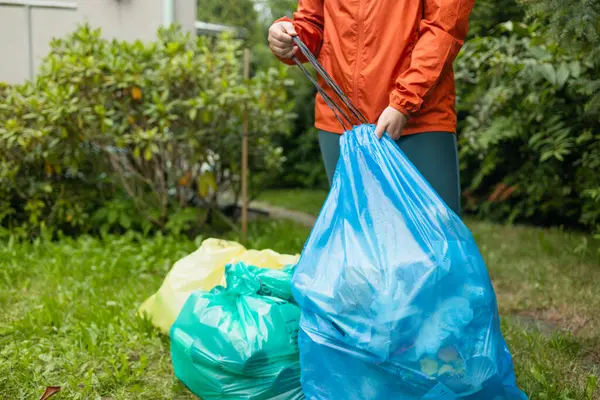 カラーパッケージの種類によるゴミの分類 環境廃棄物のリサイクル エコフレンドリーな人々はゴミを分類します 黄色いペーパー 赤い金属 緑のガラス 青いプラスチック — ストック写真