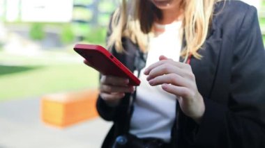 Telefonunu açık havada gülümseyen bir iş kadını. Küçük işletme girişimcisi cep telefonuna bakıyor ve ofis arkadaşlarıyla konuşurken gülümsüyor. Yüksek kalite 