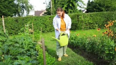 Bahçıvanlık tarım kavramı. Kadın bahçıvan elinde su bidonu ve sulama bitkisi tutuyor. Bahçede kız bahçıvanlığı. Ev yapımı organik gıda. Yerel bahçe temiz sebze üretiyor.