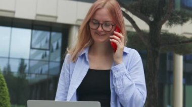 Şirket kadını portresi ofis binasına yürürken telefona cevap veriyor. İş kadını birini arıyor. Yüksek kalite 