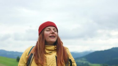 Rahatlamış 300 'lü yaşlarda, sırt çantalı, meditasyon yapan, uçurumda temiz hava soluyan ve dağdaki manzarayı seyreden, yürüyüşten sonra dinlenen, yolculuğun tadını çıkaran bir kadın. Yüksek kalite 4k görüntü