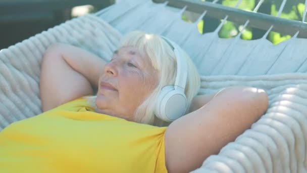 Senior Blonde 50S Woman Listening Music Lying Hammock Outdoors Terrace — Stock Video
